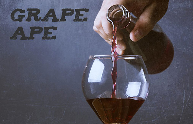 A hand pours a red wine, that has flavors played off of the Grape ape strain, into a wine glass.