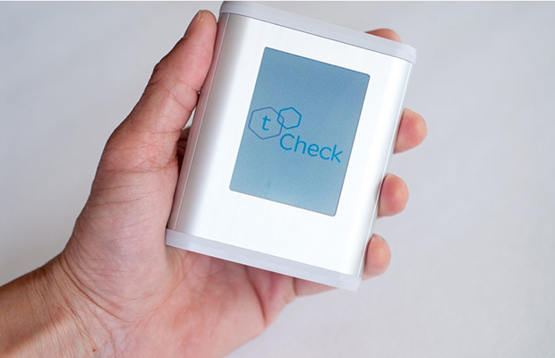 A hand holds the tCheck device which helps people dose their edibles correctly
