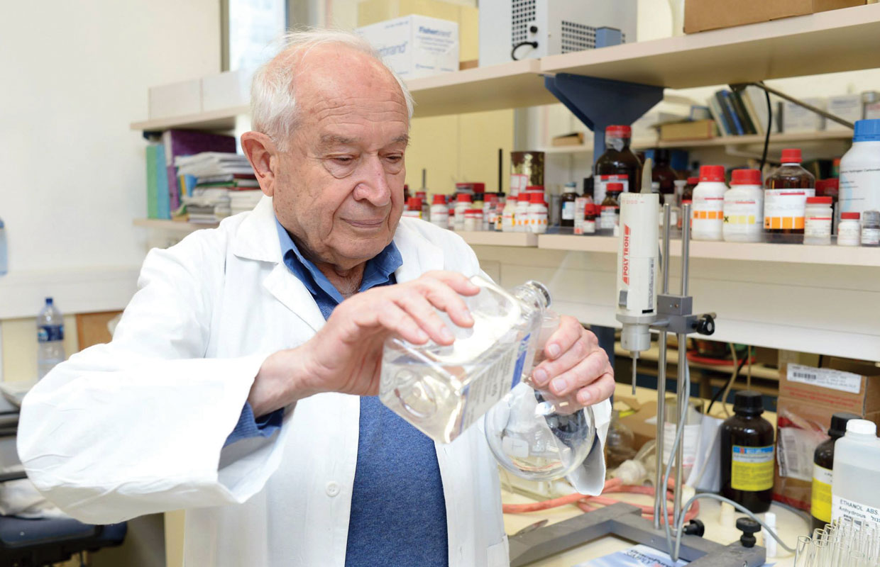 Dr. Mechoulam of Israel pours a substance from one glass jar to another while speaking with Cannabis Now about CBD and the future of marijuana.