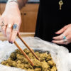 A bud tender pulls out large nugs from a bag with wooden tongs.