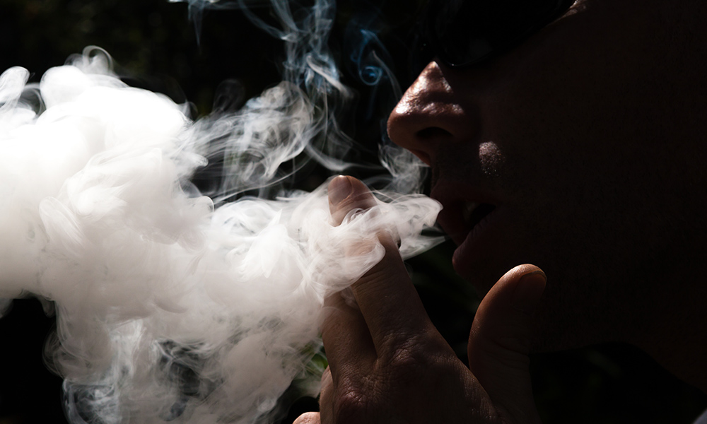 Man exhaling a large plume of smoke a cannagar